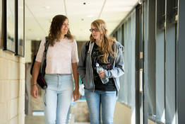 Two students chatting as they walk along the corridor in the School of Modern Languages. 